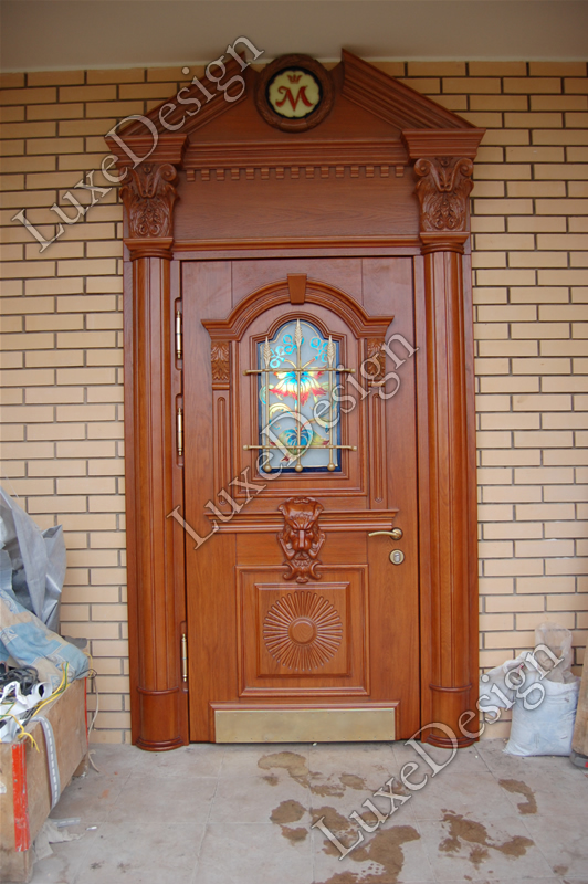 Парадная дверь с массивом дерева, стеклом и коваными элементами